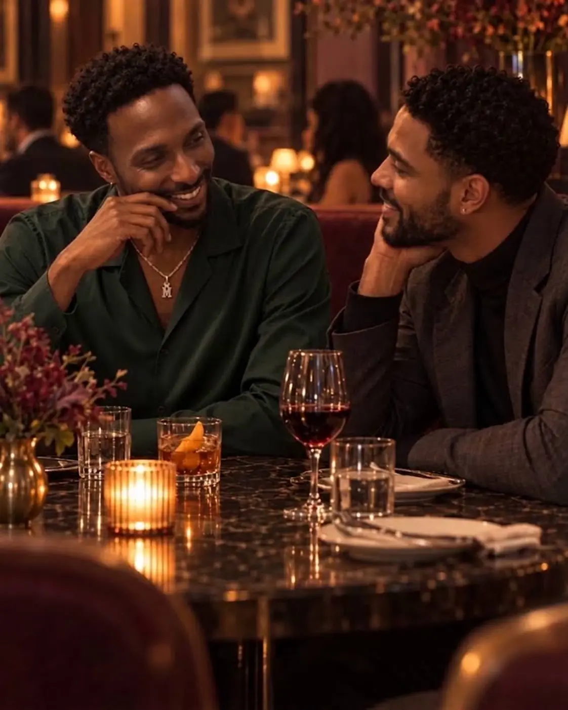 Two men sharing a relaxed laugh during a candlelit restaurant date